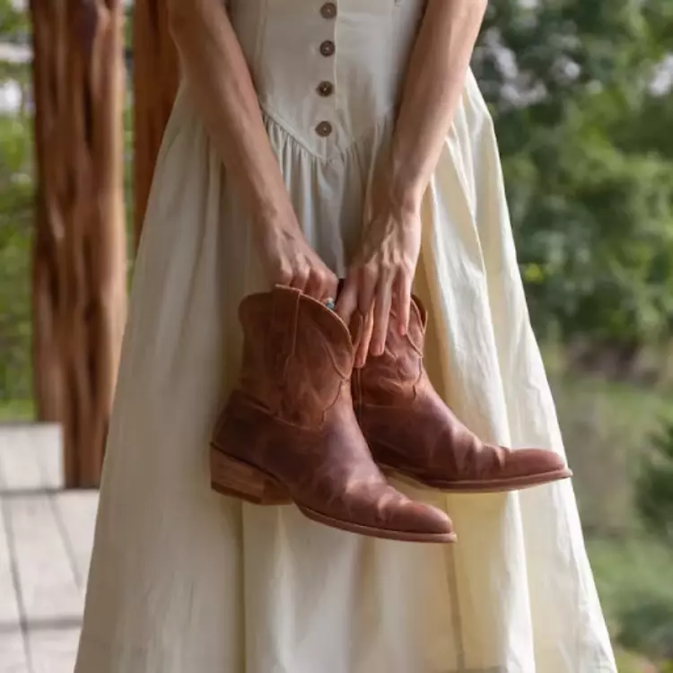 Woman in a white dress holding a pair of booties