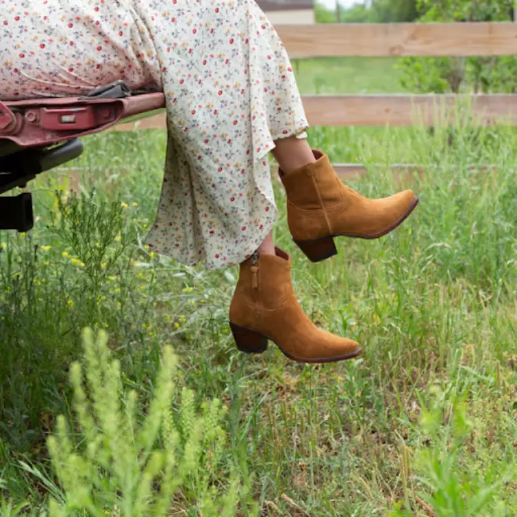 Woman in a field with wildflowers wearing suede boots