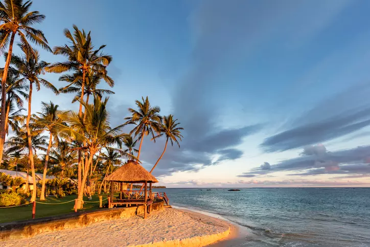 Beautiful sunset over a typical Fijian beach hut surrounded by palm trees at the coral coast beach in the south of Viti Levu, Fiji Island, Melanesia, Oceania, most beautiful countries in the world