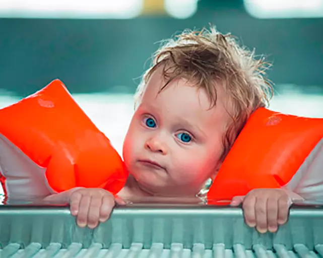 baby with armbands in swimming pool
