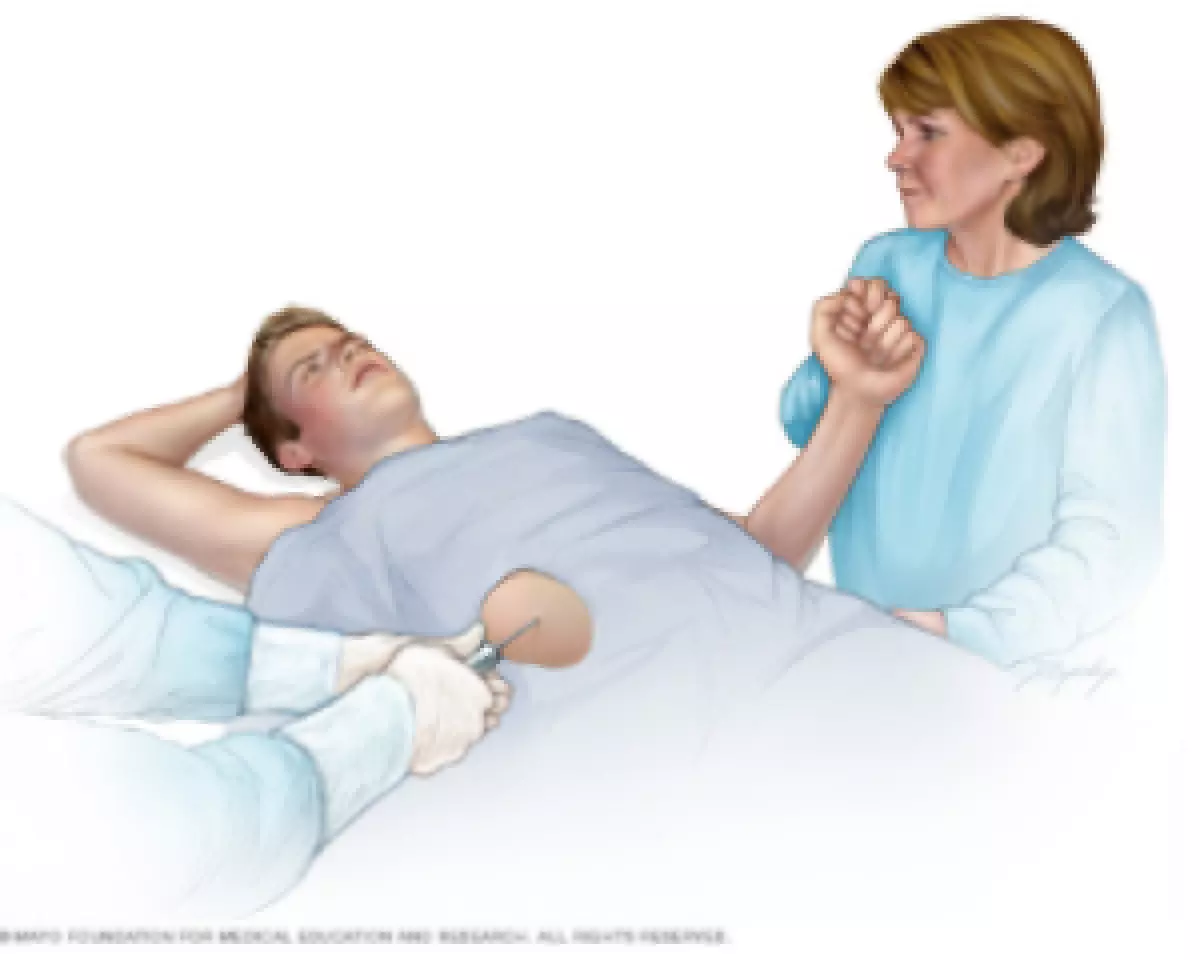 An illustration showing a patient receiving a liver biopsy. The person lays on a table, holding hands with a visitor while a doctor inserts a needle into the patient